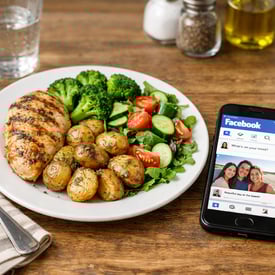 plate of food next to cell phone with facebook open on kitchen table-1